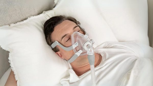 Man in bed wearing the AirFit F20 full face cpap mask | Intus Healthcare