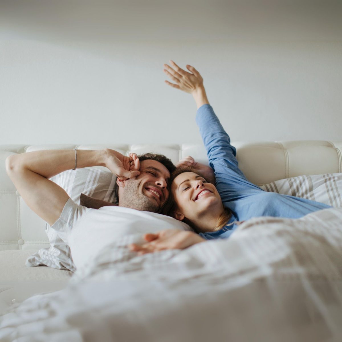 Couple laying in bed smiling | Intus Healthcare